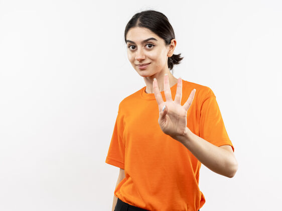 穿穿着橙色t恤的年轻女孩微笑着 手指着站在白墙上的四号女孩手指微笑四