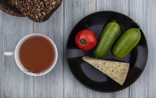 风景顶视图一杯茶与黑面包奶酪黄瓜和番茄在盘子上的灰色背景灰色红茶早晨