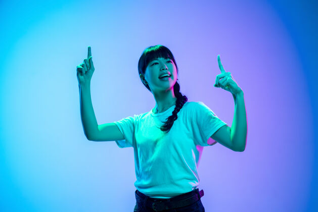 时尚在霓虹灯下的渐变蓝紫色工作室背景上的年轻亚洲女性肖像青春概念 人类情感 面部表情 销售 广告美丽的深褐色模特霓虹灯成功面部