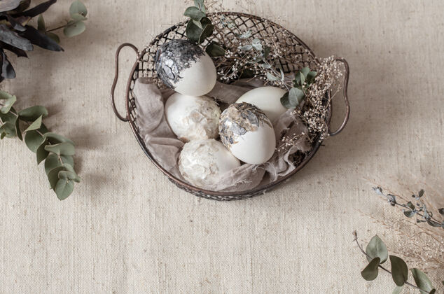 复活节彩蛋漂亮的复活节彩蛋放在一个用干花装饰的篮子里复活节快乐节日构图顶视图