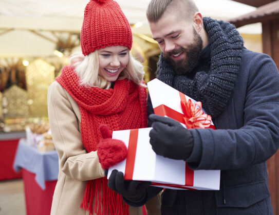 站着在圣诞市场上打开大礼物冬天的衣服盒子礼物