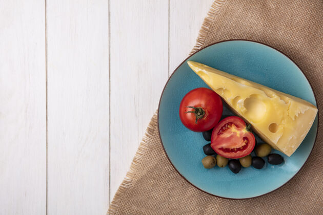 奶酪顶视图复制空间马斯丹奶酪与西红柿和橄榄在一个蓝色的盘子上米色餐巾白色背景米色蓝色盘子