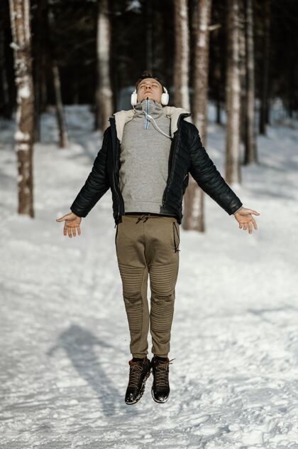 跳跃冬季在大自然中跳跃的人的正面视图人姿势户外