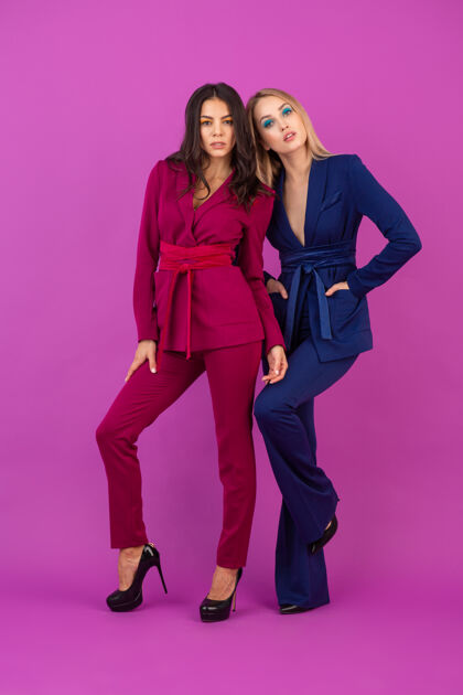 夹克高级时尚风格紫罗兰色墙壁上两位魅力四射的女士 身着紫色和蓝色的时尚多彩晚礼服 朋友们一起玩乐 时尚潮流春天时尚时尚