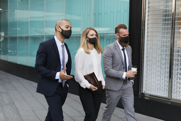一起戴着医用口罩的商务人士走向办公室户外团队安全