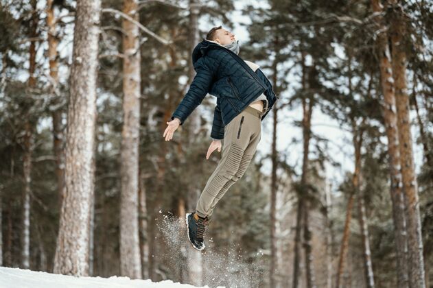 快乐冬季在大自然中跳跃的人的侧视图男个人冬天
