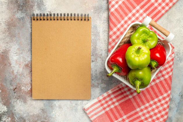 甜椒顶视图绿色和红色的辣椒在塑料篮笔记本红色桌布裸体表面青椒蔬菜塑料