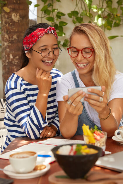 同事多民族女性在手机上看喜剧片的形象眼镜混合空间连接