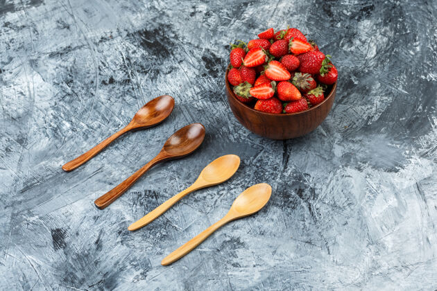 勺子侧视图一碗草莓和木制勺子在深蓝色大理石表面水平水果顶部水果