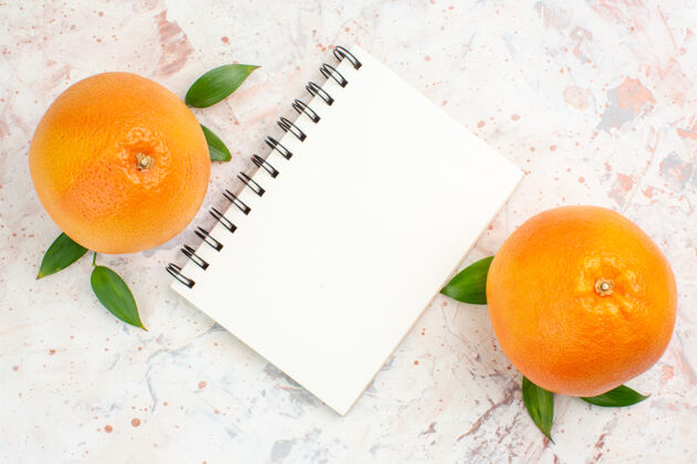 新鲜顶视图新鲜橙子笔记本上明亮的孤立表面多汁叶子柑橘