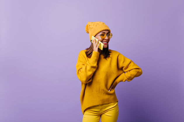 成人女孩喜欢橙色 穿着时髦的服装为新的snapportrait拍照模特在黄色的电话里交谈 友好的微笑奇迹现代黑发