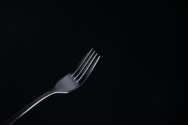 餐厅前视钢叉在黑色表面与自由空间钢叉吃饭抹刀