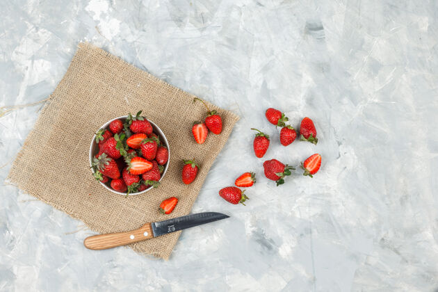 甜点俯视图：一碗草莓放在一个袋子上 刀放在白色大理石表面饮食特写早餐