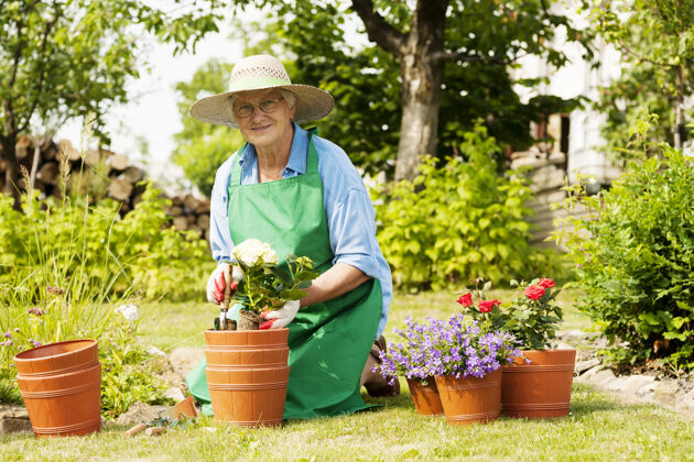 绿色花园里拿着花的老妇人花盆老年人欢快