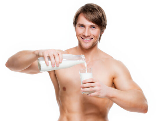 赤膊一个年轻英俊的肌肉男把牛奶倒进玻璃里的画像-隔离在白色的墙上营养微笑吸引力