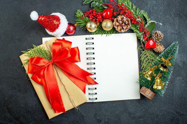 圣诞心情圣诞心情与杉木树枝圣诞老人帽子圣诞树红丝带笔记本上的黑暗背景蝴蝶结树枝笔记本