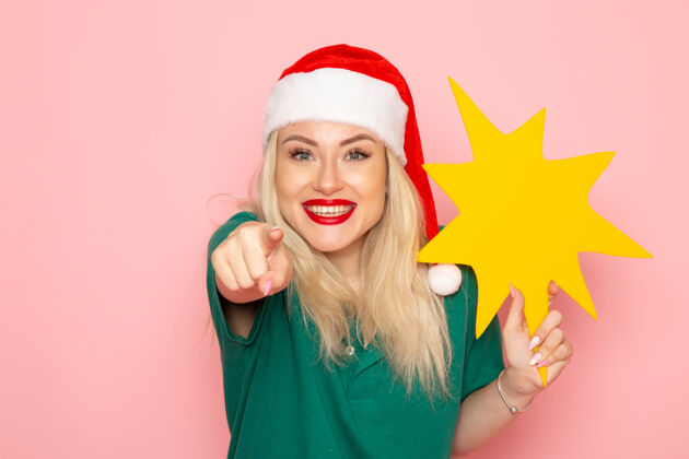 圣诞节正面图年轻女性手持粉色墙壁上的黄色大人物模特女子圣诞假期照片新年彩照女人风景身材