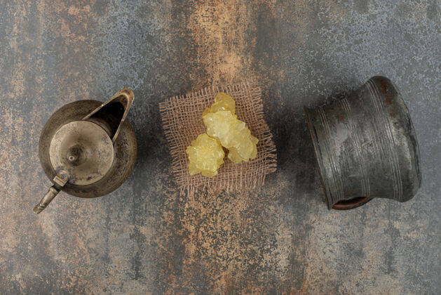 好吃在大理石墙上放着两个古老的水壶和一片黄色的白糖糖古老美味