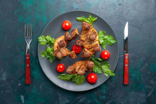 食物俯视图在深蓝色的背景上 盘子里放着切成片的熟肉 还有绿色和樱桃番茄樱桃肉西红柿