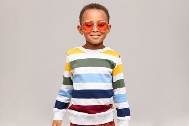 年轻美丽 时尚 时尚的概念照片中快乐时尚的非洲男孩穿着时尚的条纹毛衣和时髦的圆粉色太阳镜 快乐地微笑着小学龄前儿童孩子