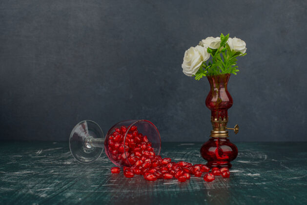 玻璃一杯石榴籽和花瓶里的白花种子花有机