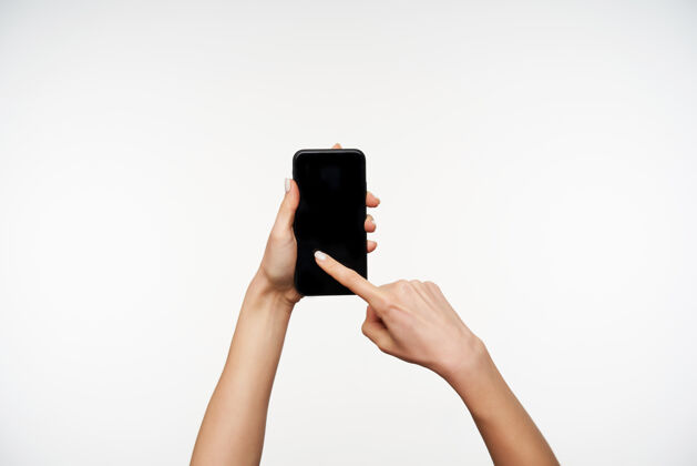 小工具年轻女子手举着手机 食指在屏幕上滑动 在白色屏幕上摆姿势的横向肖像手臂抬起年轻