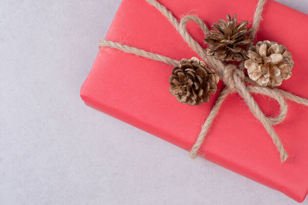 松果红色圣诞礼盒 白色上有三个松果松树礼物顶部视图