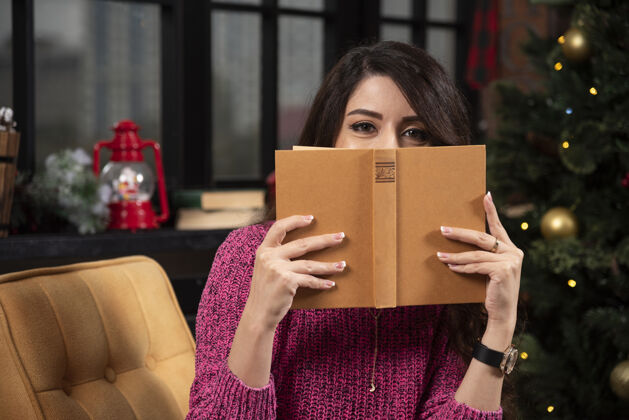 青年一个年轻漂亮的女孩藏在一本打开的书后面的画像微笑女性知识