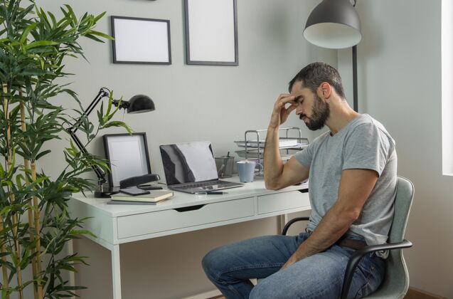 男性坐在书桌旁的疲倦的人水平家庭办公室远程工作