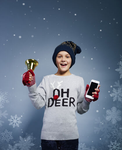 手机带着圣诞铃和手机的男孩庆祝活动幸福微笑