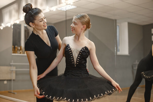 女孩穿着黑色芭蕾舞服装的可爱的小芭蕾舞演员年轻的女士在房间里跳舞和老师一起上舞蹈课的女孩表演裙子芭蕾舞