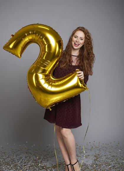 微笑尖叫的女人拿着气球庆祝她的公司的两岁生日生日肖像幸福