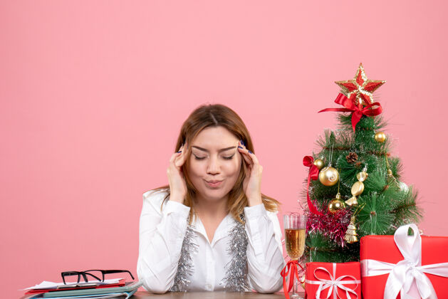 工人女职工围坐在粉红色的圣诞礼物旁头痛的正视图坐着粉色女性