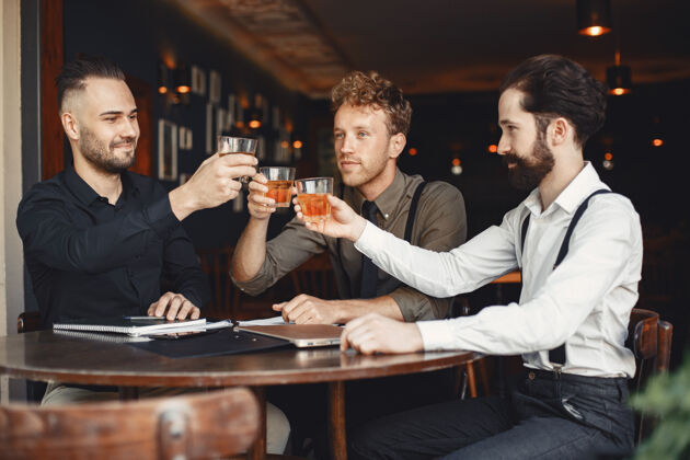 市场营销谈判中的商人坐在桌边喝酒的男人朋友们在聊天合作伙伴经理玻璃