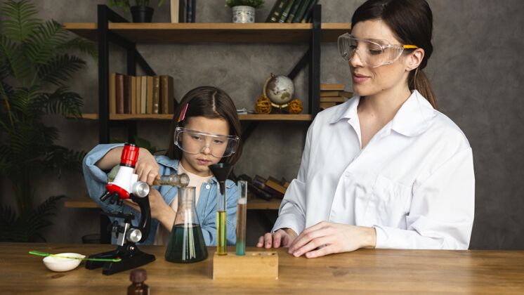 科学家女孩和女老师用试管和显微镜做科学实验考试实验安全
