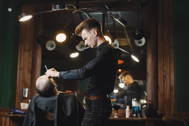 剪有胡子的男人有客户的理发师刮胡子的男人服务时尚胡子