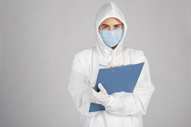 年轻人戴着医用面罩的医生冠状病毒主题隔离在白墙上穿着防护服的女人临床护士医学