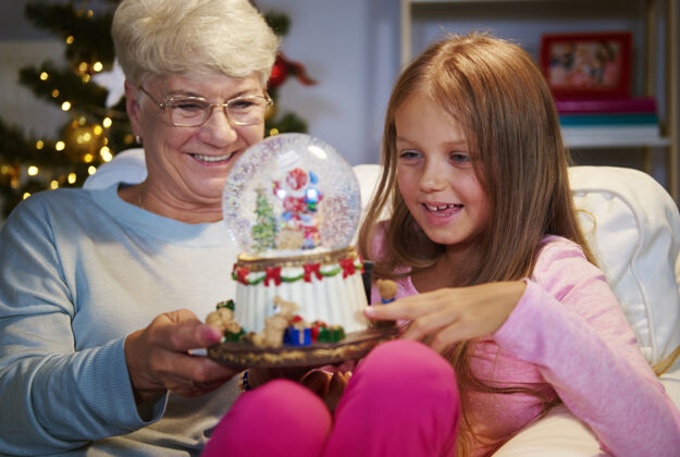 情感老太太带着孙女拿着圣诞装饰品抱着玩得开心向上