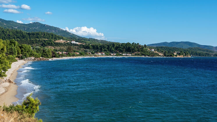 户外希腊爱琴海海岸 多岩石的小山上长着树木和灌木 建筑物位于海岸附近景观山天空