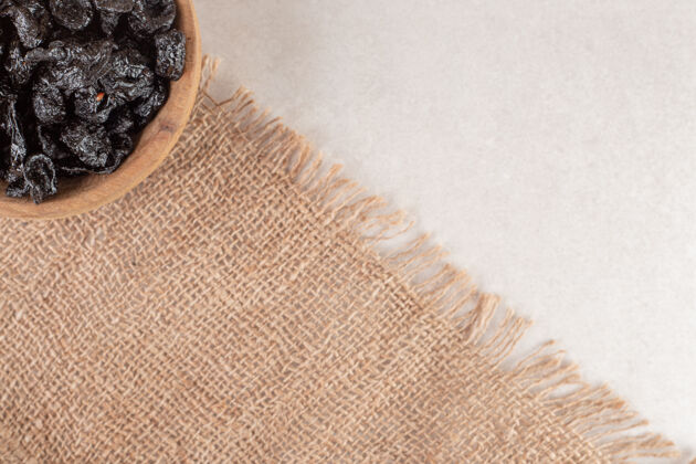 质量黑李子放在一块粗麻布上的木杯里清淡简约食物