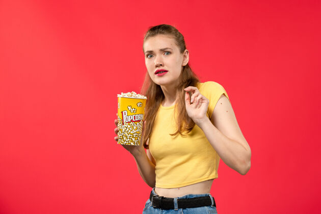 电影正面图年轻女性在电影院拿着爆米花包上红墙电影院电影院小吃女性趣味电影小吃年轻人年轻女性