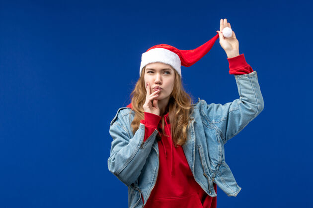 视图正面图：年轻女性 戴着红色圣诞帽 背景是蓝色的圣诞色开朗参赛者年轻人