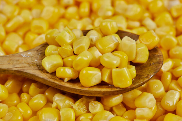 种子白桌子上放着一堆用木勺煮的甜玉米木材有机黄色