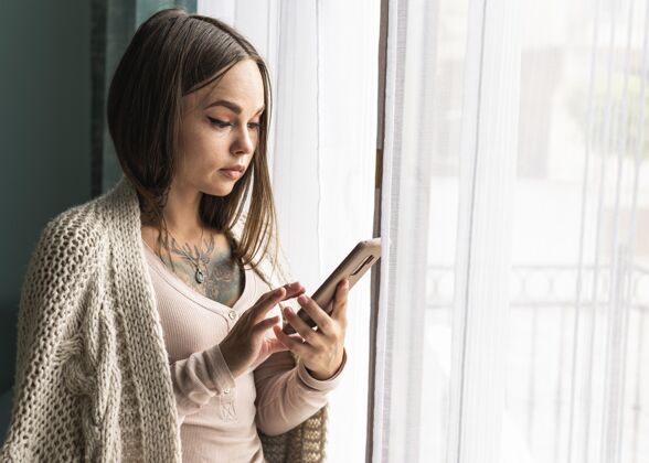 Ncov流感大流行期间 家里靠窗户使用智能手机的妇女预防隔离智能手机