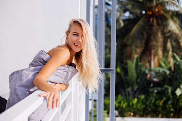 露台年轻的金发时尚的欧洲女人穿着毯子在热带阳台上迎接日出女士无忧无虑时尚模特