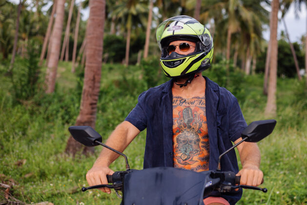 滑板车在热带丛林的田野上纹着红色摩托车的壮汉户外交通人