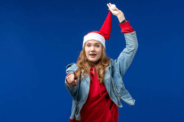 年轻女性正面图：年轻女性 戴着红色圣诞帽 背景是蓝色的圣诞色参赛者快乐红色