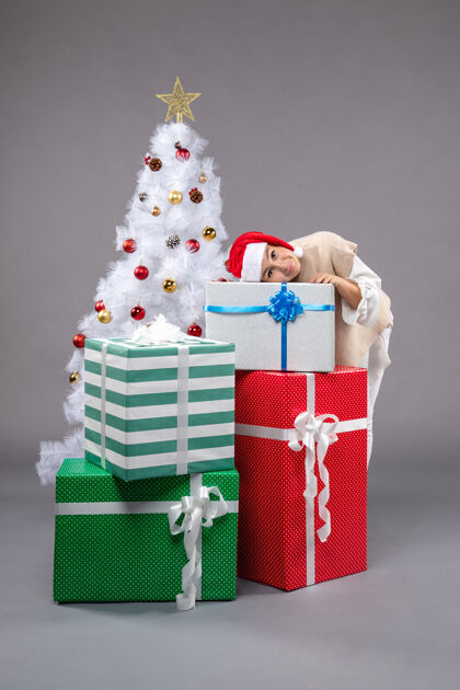 圣诞漂亮的女人在灰色的礼物周围圣诞老人礼物长袜