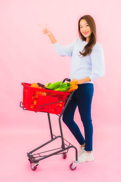 家庭主妇一幅美丽的亚洲年轻女子的画像 粉红色的隔离墙上 篮子里放着水果蔬菜和杂货有机购买新鲜