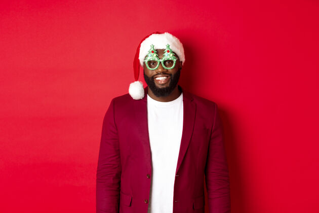 手势戴圣诞帽戴派对眼镜的滑稽黑人庆祝圣诞节圣诞老人正式男人